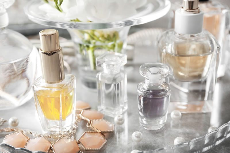 Glass tray with perfume bottles and necklace, closeup